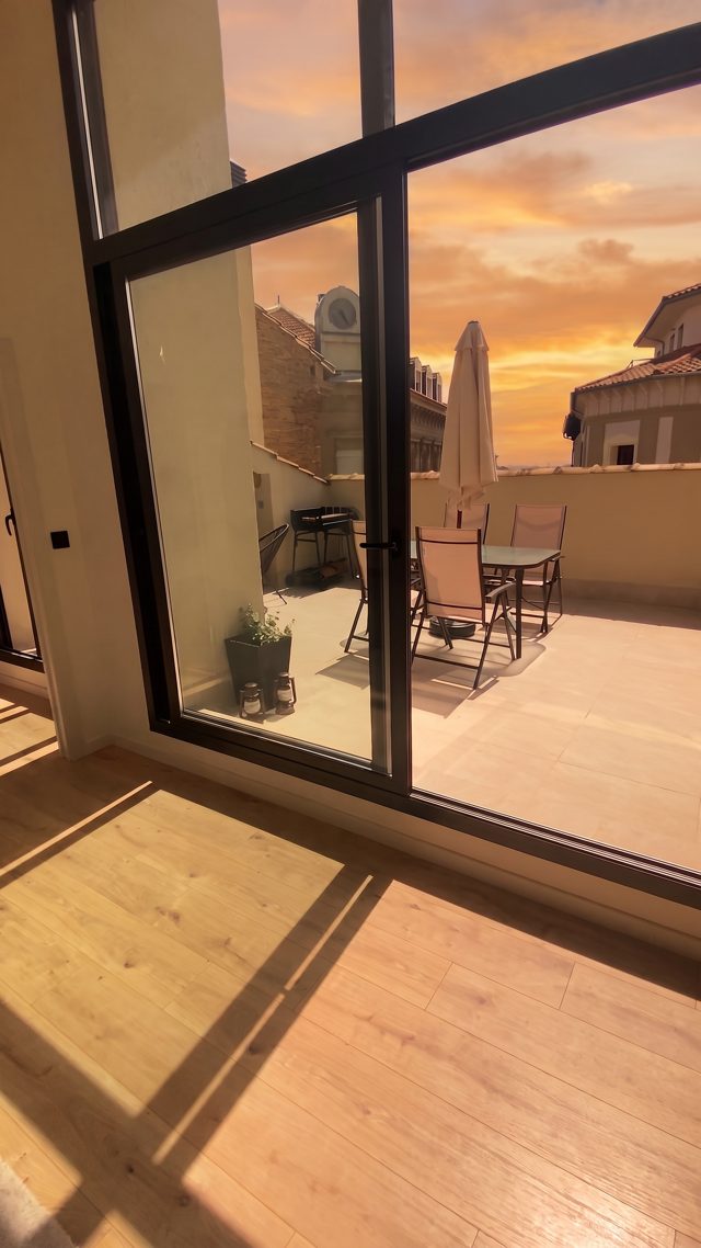 Salón con ventanal a la terraza, versión con IA a la hora dorada